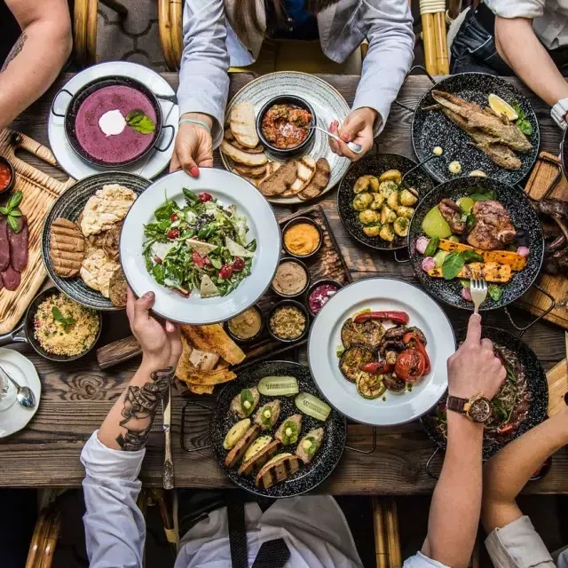 People sitting at a dining table, sharing food.