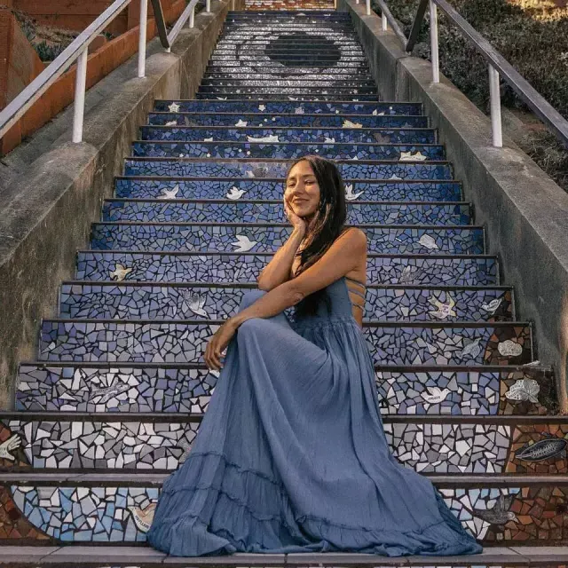 A woman poses sitting on the 16th Avenue tiled stairs 在 Sunset 社区 of San Francisco.